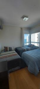 two beds in a bedroom with a view of the city at Mirador del Golfo Puerto Madryn in Puerto Madryn