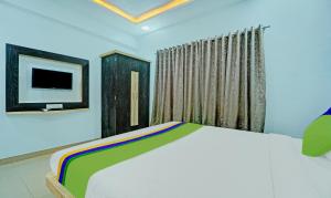 a bedroom with a bed and a tv on the wall at Treebo Trend Kuber Palace in Mahabaleshwar