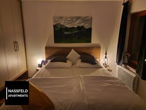 a bedroom with a large bed with a painting on the wall at Haus Anja NASSFELD APARTMENTS in Sonnenalpe Nassfeld