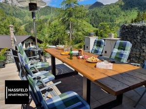 a wooden table and chairs on a patio with mountains at Haus Anja NASSFELD APARTMENTS in Sonnenalpe Nassfeld