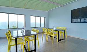 a dining room with yellow chairs and tables and a chalkboard at Treebo Trend Kuber Palace in Mahabaleshwar