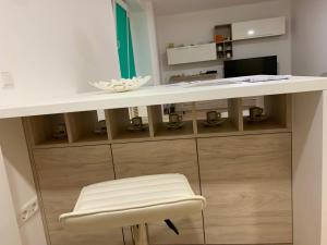 a white desk with a stool and a table and chair at Jaunimo Apartamento in Alytus