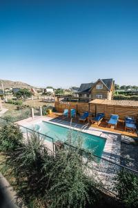 a swimming pool with blue chairs and a house at OHANA in Sierra de la Ventana
