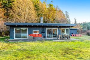 a blue house with red furniture in a yard at Lopez Island Mud Bay Waterfront home in Islandale