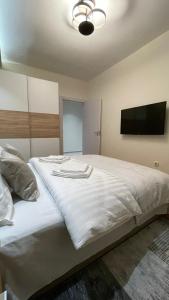 a bedroom with a large white bed with a flat screen tv at Filip Luxury Suite in Belgrade