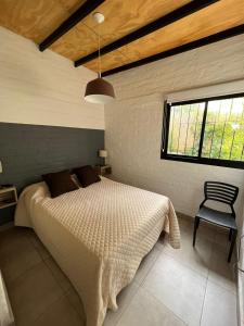 a bedroom with a bed and a window and a chair at Andrea Houses in Chacras de Coria