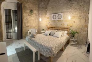 1 dormitorio con cama y pared de piedra en BF BOUTIQUE JEREZ, en Jerez de la Frontera