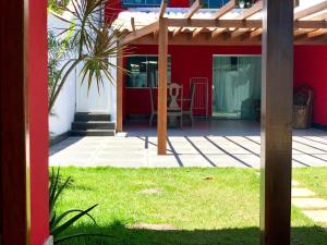 a patio with a red house with a wooden pergola at Casa espaçosa 15h 800m praia in Porto Seguro