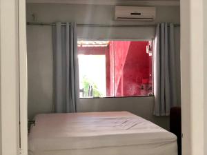 1 dormitorio con cama y ventana en Casa espaçosa 15h 800m praia, en Porto Seguro