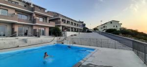 eine Person in einem Pool neben einem Gebäude in der Unterkunft Elicriso in Castelsardo