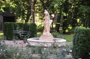 a statue of a woman sitting on a fountain in a park at Zamek Podewils Krag in Krąg