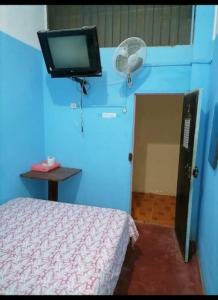 Habitación con cama y TV en la pared. en Hospedaje Independencia Pucallpa, en Pucallpa