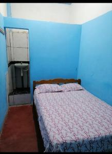 um quarto com uma cama com uma parede azul em Hospedaje Independencia Pucallpa em Pucallpa