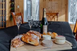 una mesa con una botella de vino, pan y copas de vino en Le Rêveur⎮Ski, Spa, Plein-Air et Détente, en Petite-Rivière-Saint-François