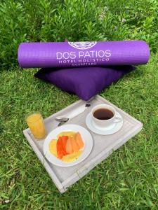 a tray with a plate of fruit and a cup of coffee at Dos Patios Querétaro Curamoria Collection in Querétaro