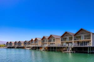 a row of houses on a dock in the water at Marsden Lake Resort Central Otago in Cromwell
