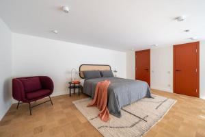 a bedroom with a bed and a red chair at Bright designer Loft in the city center in Rīga
