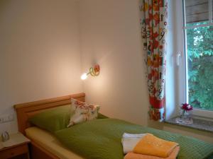 ein kleines Schlafzimmer mit einem grünen Bett und einem Fenster in der Unterkunft Ferienhof Rösch in Bad Wurzach