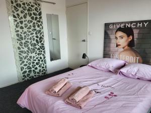 a bed with pink sheets and a poster of a woman at loft avec parking et terrasse in Chamalières