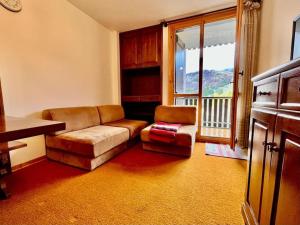 een woonkamer met een bank, een stoel en een raam bij Su In Cima - Piancavallo in Piancavallo