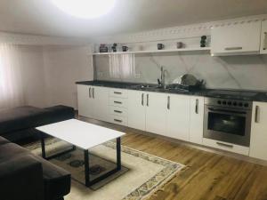 una cucina con armadi bianchi e un tavolo in una stanza di Green house, 1 bedroom & 1 kitchen apartment, located in Elbasan city center a Elbasan