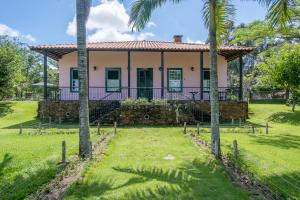 a house with palm trees in front of it at Sítio Paraíso Beach Tennis in Vassouras