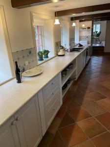 a large kitchen with white cabinets and a tile floor at Hygge Ho - mitten in der Natur mit Sauna und Spa in Blåvand