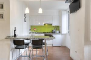 een keuken met witte kasten en een aanrecht met krukken bij BmyGuest - Castelo Stylish Flat in Lissabon