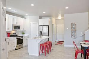 une cuisine avec des placards blancs et des tabourets de bar rouges dans l'établissement Three-Bedroom Townhouse, à Washington