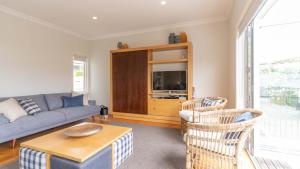 a living room with a couch and a tv at Spacious Sunny Family Home in Akaroa in Akaroa