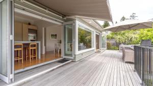 an outdoor deck with a kitchen and a dining room at Spacious Sunny Family Home in Akaroa in Akaroa