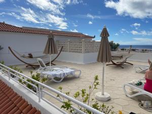 un patio con sillas y sombrillas en la azotea en Luxury Diamond - Ocean view, Big terraces, Air Con, Wifi, en Los Cristianos