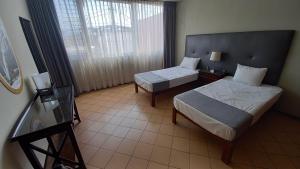 um quarto de hotel com duas camas e uma janela em LA CASA DE LOS RIVAS, AMPLIA, CÓMODA, BIEN UBICADA em Tepic