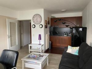a living room with a couch and a clock on the wall at Green House Strassen in Strassen