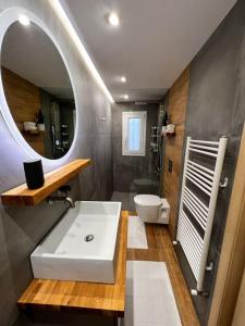 een badkamer met een wastafel, een toilet en een spiegel bij Homevision - Stylish & Serene Condo - City Center in Thessaloniki