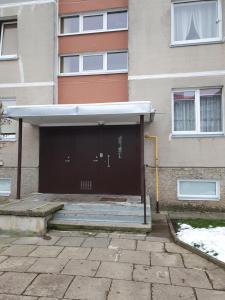 a building with a brown door and stairs in front at Dainai 1-Bedroom apartament. in Šiauliai