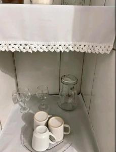 uma prateleira com copos e copos numa mesa em Estúdio ( Kitnet ) confortável em Ouro Preto