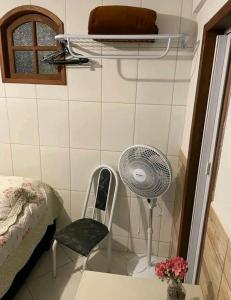 Habitación pequeña con ventilador y silla en Estúdio ( Kitnet ) confortável en Ouro Preto