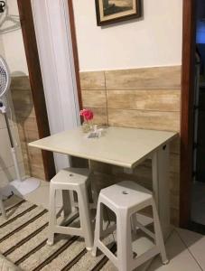 una mesa blanca y dos taburetes en una habitación en Estúdio ( Kitnet ) confortável en Ouro Preto