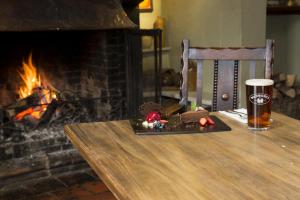 a glass of beer sitting on a table next to a fireplace at Hadley Bowling Green Inn in Droitwich