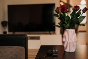 a vase of roses sitting on top of a table at Loft Riva II - Terrasse, Smart TV, Klimaanlage, Parkplatz frei, Minibar in Hamm