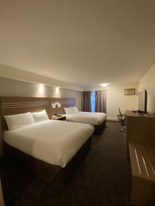 a hotel room with two beds and a television at Chalet Continental Motel in Valemount