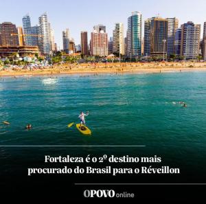 uma pessoa a montar uma prancha de surf na água perto de uma praia em AP BEACH CLASS FORTALEZA em Fortaleza