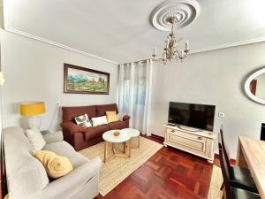 a living room with a couch and a tv at La Casa de la Buganvilla in Gijón