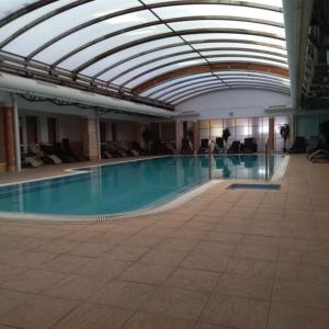 a swimming pool in a building with a glass ceiling at Bóbita Apartman in Zalakaros