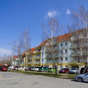 un gran edificio con coches estacionados frente a él en Bóbita Apartman, en Zalakaros