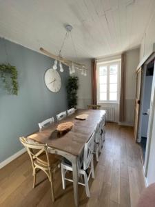 een eettafel met stoelen en een klok aan de muur bij House in the center and near the beach in Rivedoux-Plage