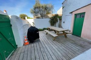 een houten terras met een houten bank en een groene deur bij House in the center and near the beach in Rivedoux-Plage