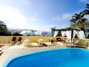 a swimming pool with chairs and a table at Pousada Vila do Navegante in Bombinhas