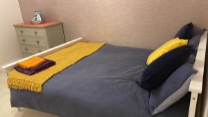 uma cama com um cobertor amarelo e azul e uma cómoda em GOLDSTONE LONDON STUDIO WITH ACCESS TO GARDEN em Saint Mary Cray